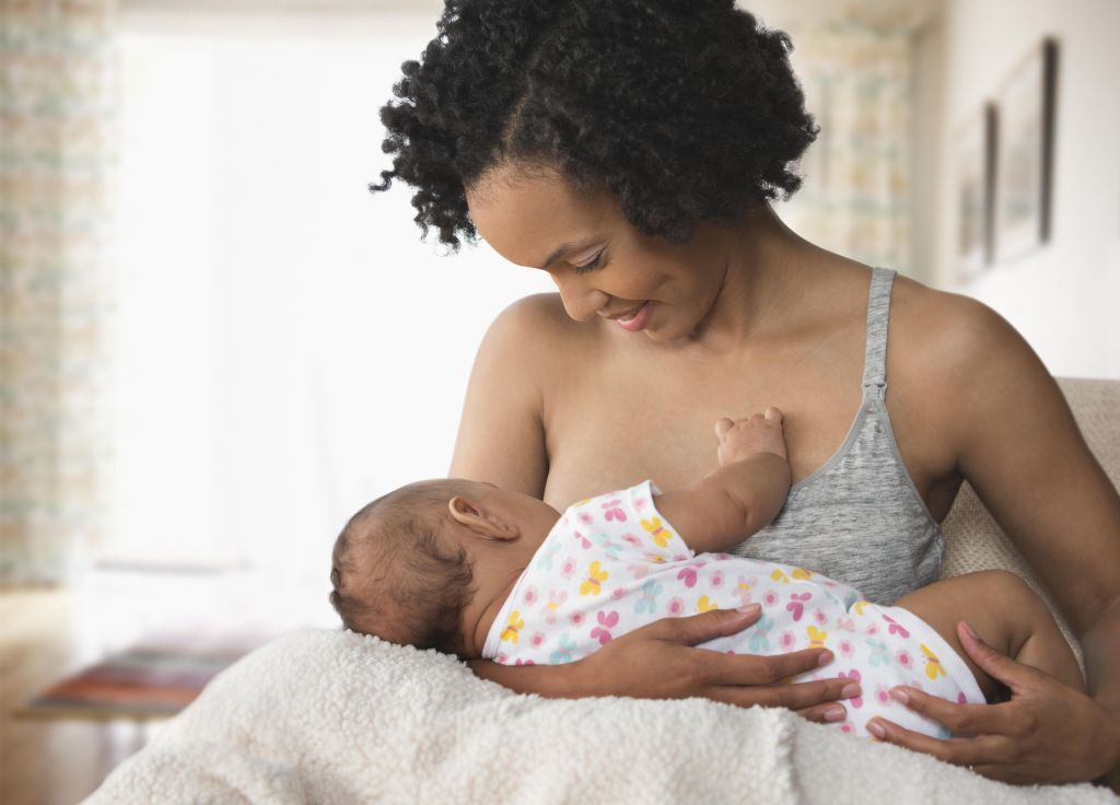 Mother breastfeeding baby in living room