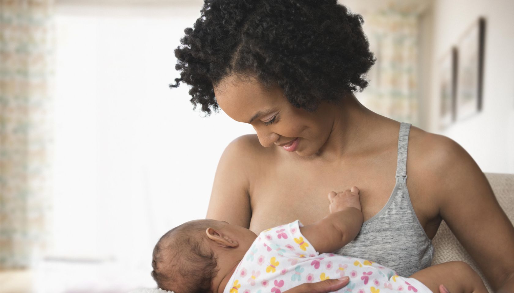 Mother breastfeeding baby in living room