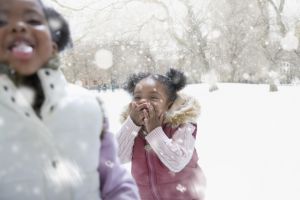 Mixed race girl playing outdoors in falling snow