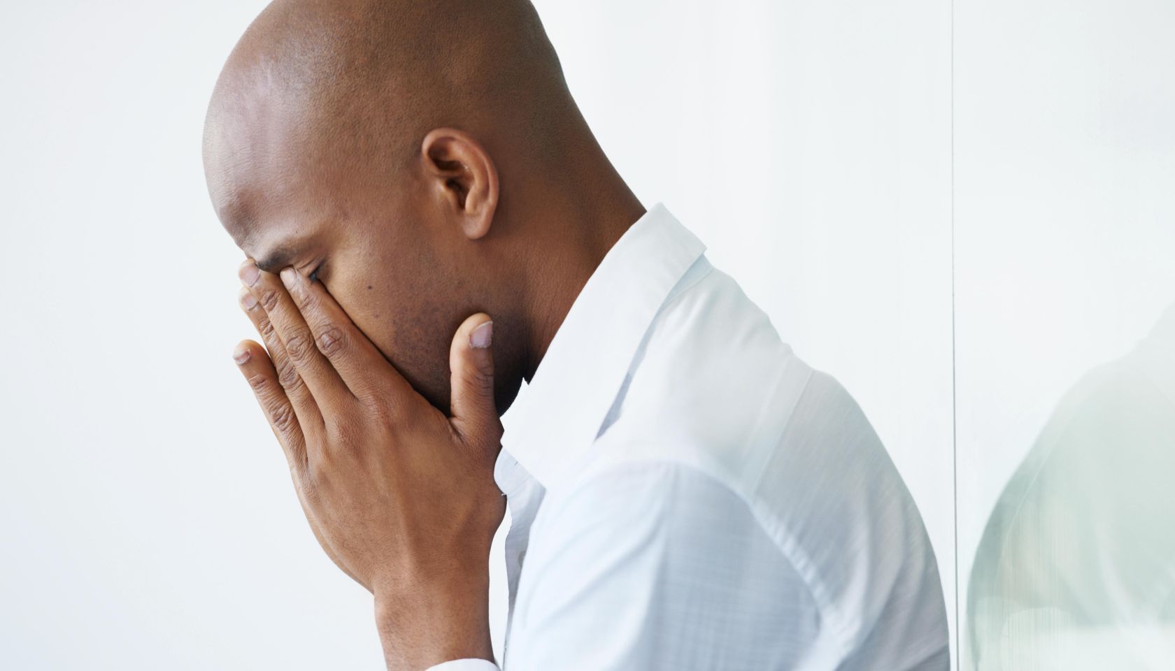 A young businessman crying with his face in his hands