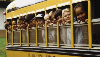 School children looking out school bus windows.