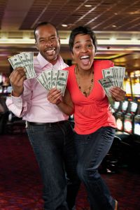 Excited couple holding cash winnings in casino