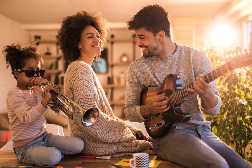 Playful black family having fun while playing musical instruments at home.