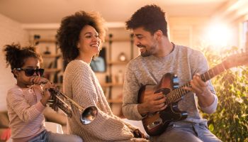Playful black family having fun while playing musical instruments at home.