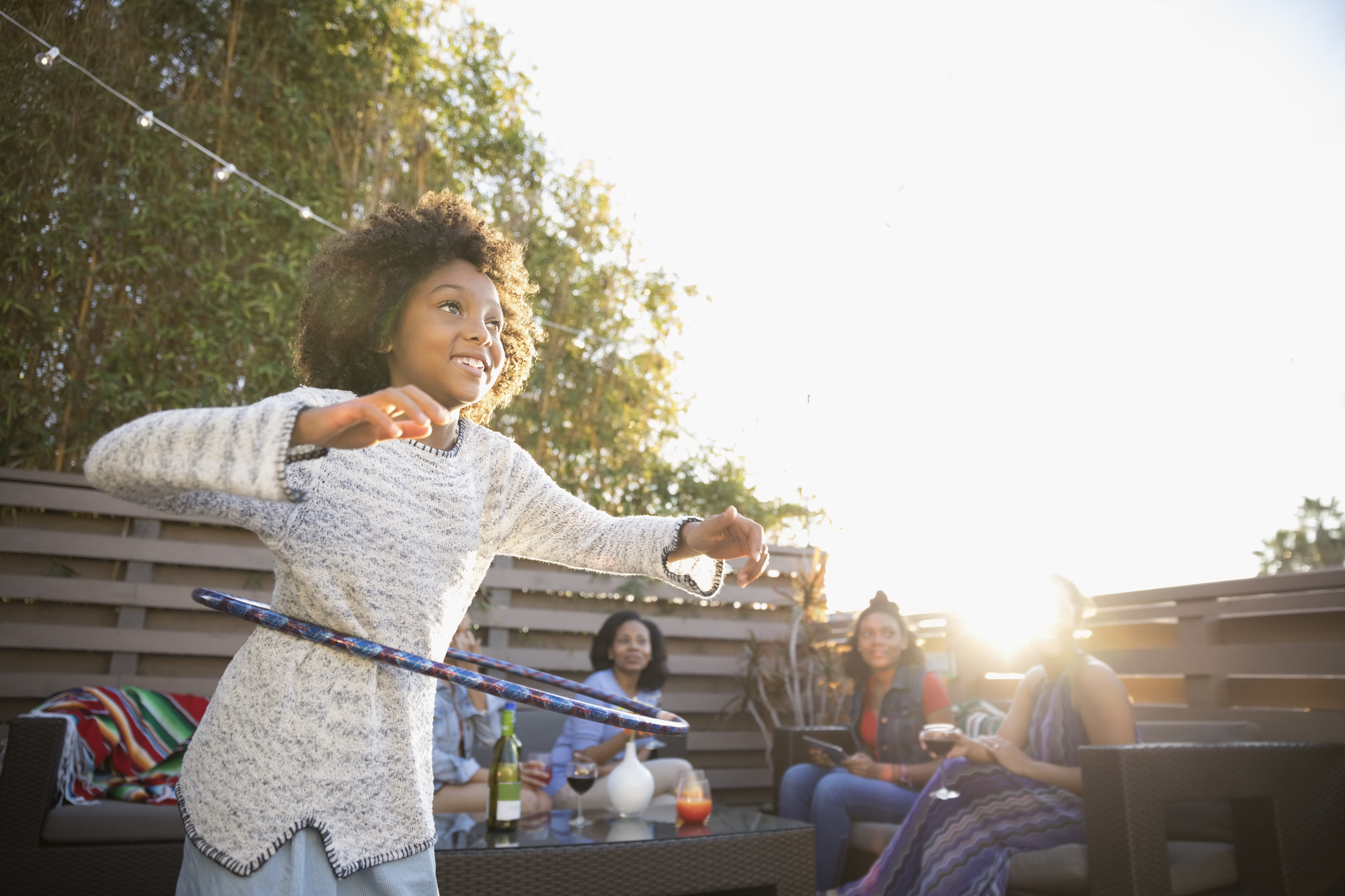 Girl spinning in plastic hoop on sunny deck