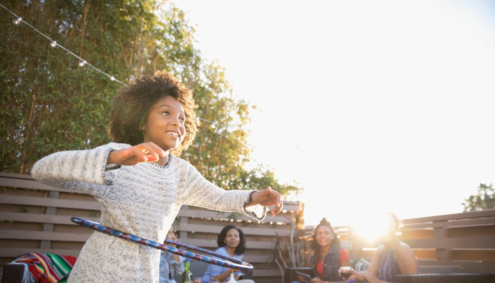 Girl spinning in plastic hoop on sunny deck