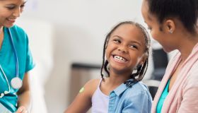 Smiling girl receives immunization from nurse