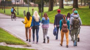 Rear view of sudents walking through the park