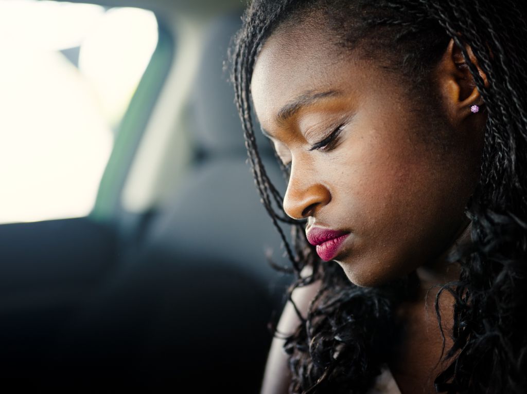 Lonely sad young African woman in car