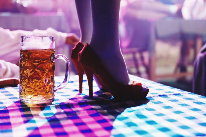 Low Section Of Woman Standing By Beer Glass On Table At Bar