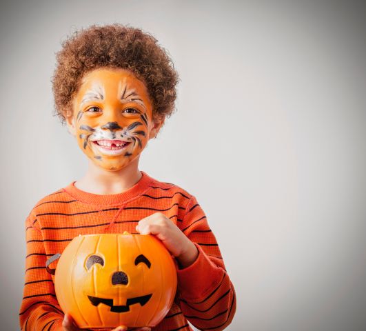 Mixed race boy with tiger costume and Halloween jack-o-lantern bucket