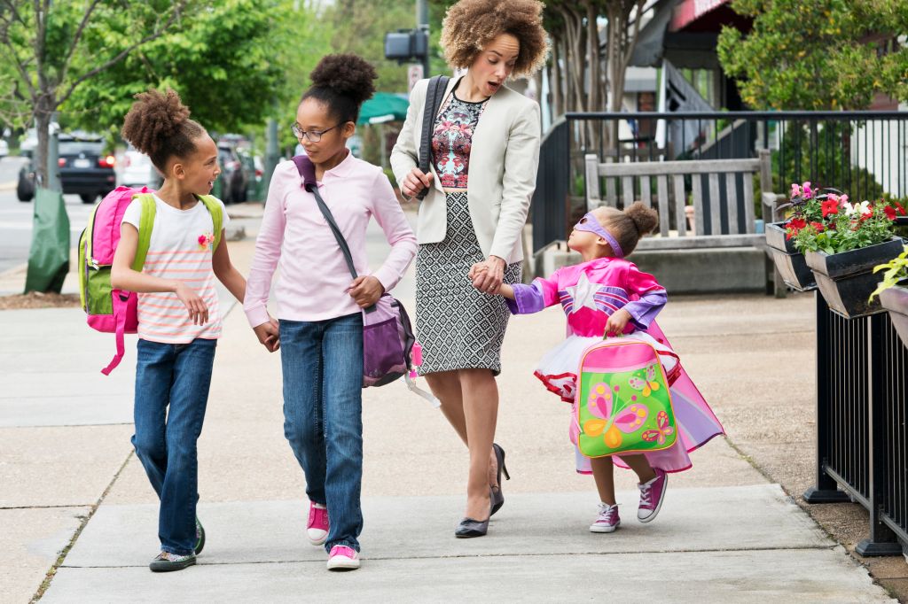 Mixed Race woman walking daughters to school in city