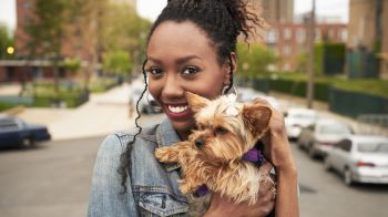 Black woman holding dog in city