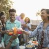African American family toasting soda glasses, enjoying barbecue on summer deck