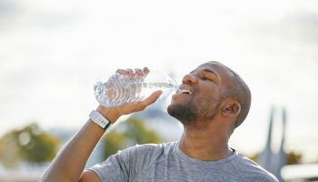 Tired man drinking water from bottle on sunny day