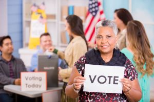 Voters register, voting in USA elections. Woman holds 'Vote' sign.