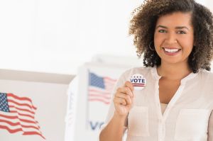 Young woman holding voting badge and smiling