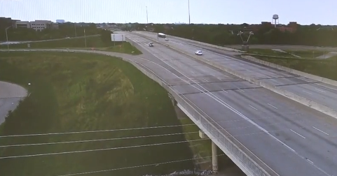 A highway with multiple lanes and vehicles traveling in both directions, with grassy areas on either side.